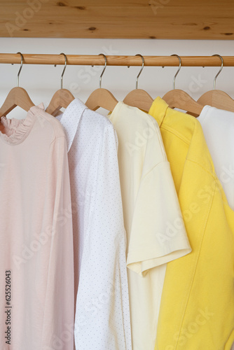 Colorful shirts on hangers in wardrobe, closeup. © Lys Owl
