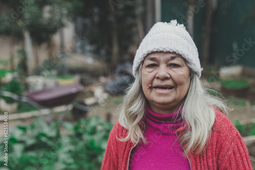 woman over 70 years old looking at the camera in a orchard, smiling, in winter