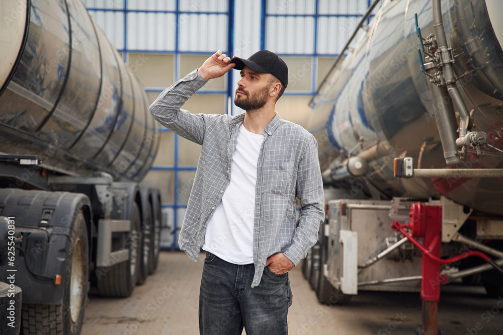 Between two vehicles. Young truck driver in casual clothes Between two vehicles. Young truck driver in casual clothes