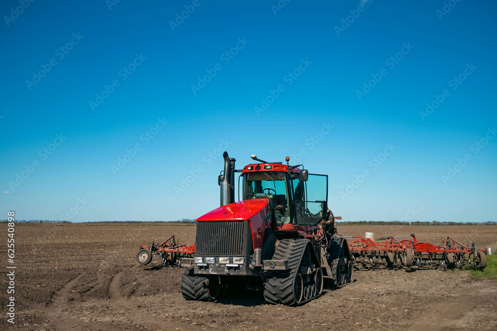 Obraz premium A large farm tractor with planting equipment in a large grain field in spring.
