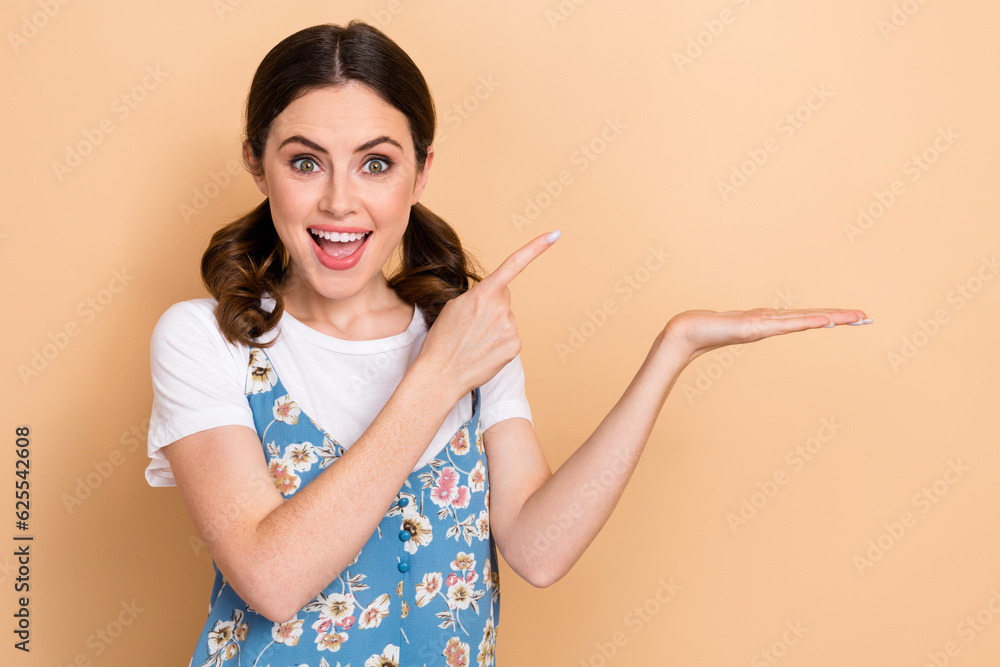 Photo of impressed overjoyed girl wear blue overall indicating at palm demonstrate product empty space isolated on pastel color background Photo of impressed overjoyed girl wear blue overall indicating at palm demonstrate product empty space isolated on pastel color background