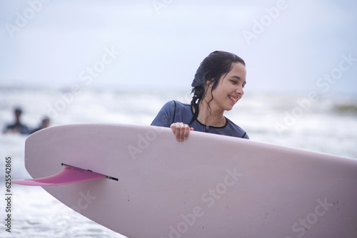 Photography Pre teen girl holding surfboard, has fun with the surfboard at the beach, outdoo