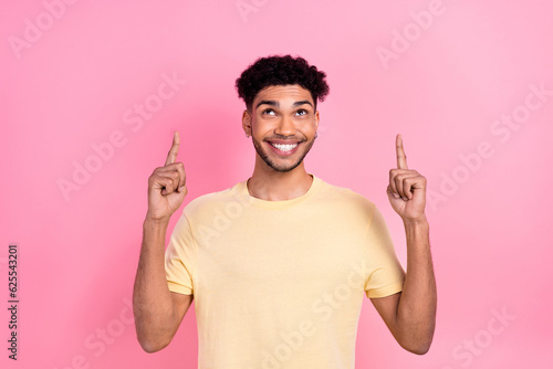 Portrait of multinational cute student man direct fingers look up empty space wear shirt isolated pink color background
