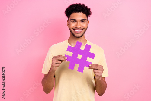 Portrait of optimistic cheerful man with afro hairstyle earrings stubble hands hold hashtag symbol isolated on pink color background