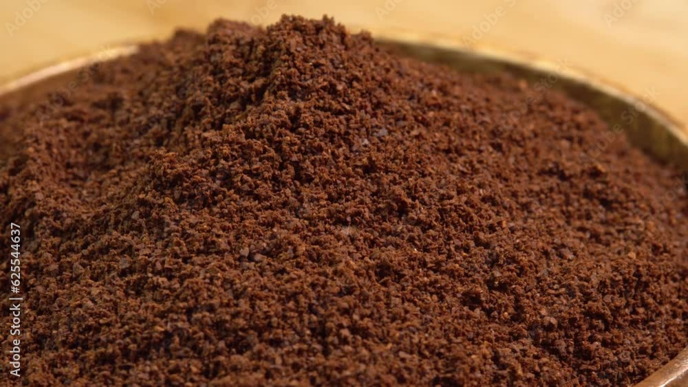 Natural ground coffee rotating in wooden bowl. Heap of fine grinding coffee powder. Invigorating coffee drink for breakfast in the morning Natural ground coffee rotating in wooden bowl. Heap of fine grinding coffee powder. Invigorating coffee drink for breakfast in the morning