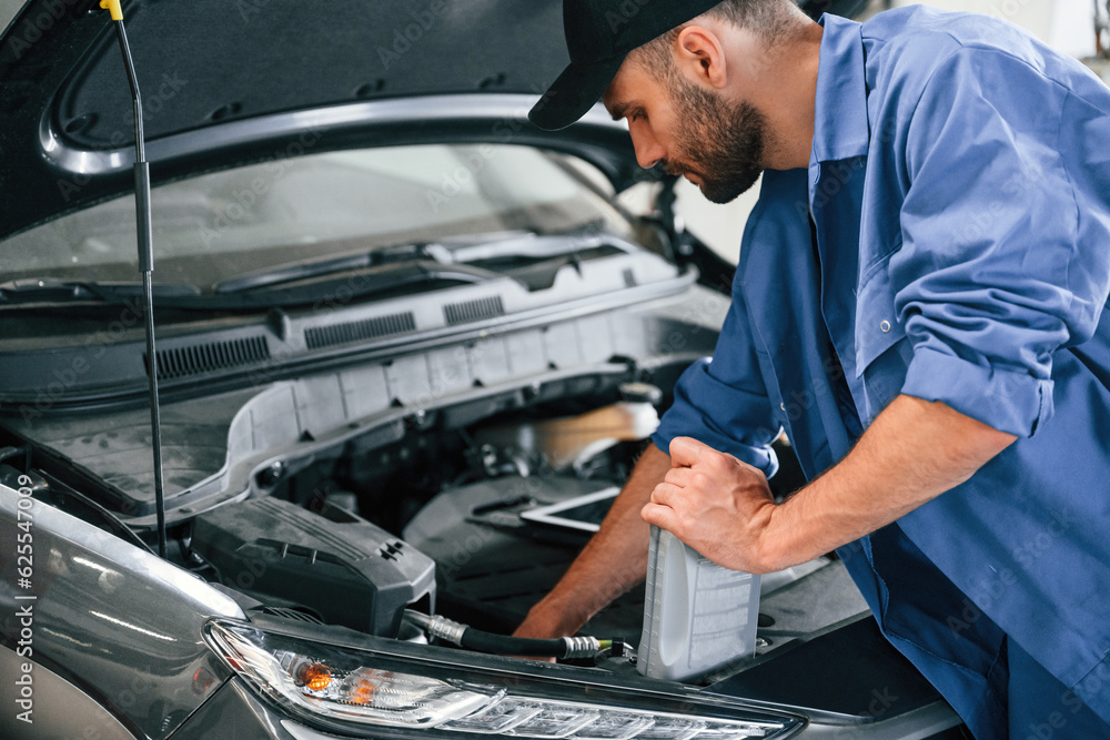 Grey colored oil can in hands. Auto mechanic working in garage. Repair service Grey colored oil can in hands. Auto mechanic working in garage. Repair service