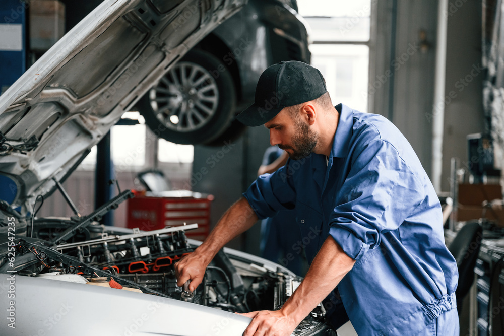 Adjusting the screws. Auto mechanic working in garage. Repair service Adjusting the screws. Auto mechanic working in garage. Repair service