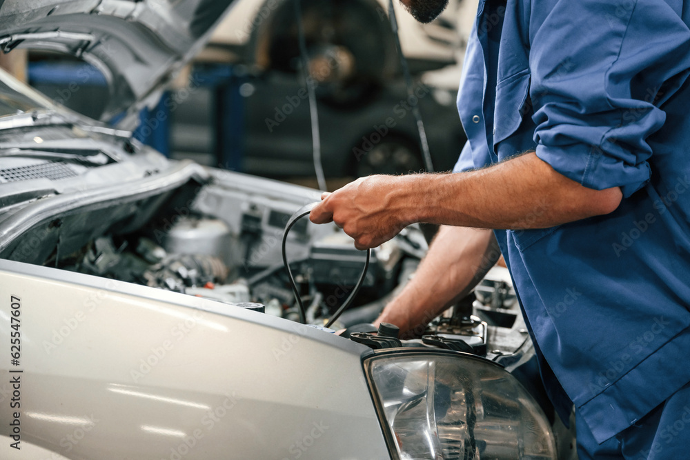 Adjusts the cable. Auto mechanic working in garage. Repair service Adjusts the cable. Auto mechanic working in garage. Repair service