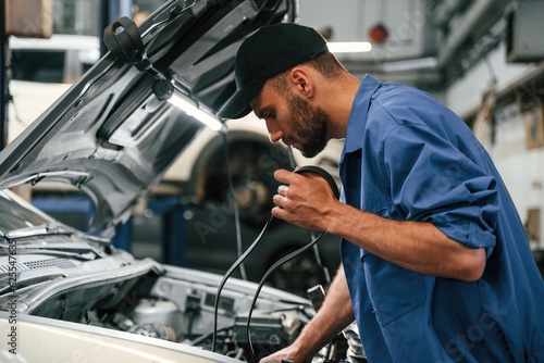 Adjusts the cable. Auto mechanic working in garage. Repair service