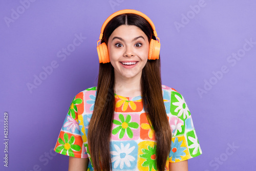 Photo portrait of pretty young girl listen music excited impressed wear trendy flower print outfit isolated on violet color background © deagreez