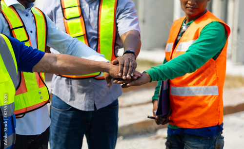 diverse construction engineering people putting hands together. Unity and teamwork concept. Asian and african american worker at factory