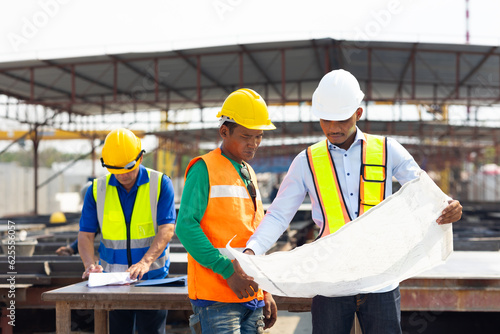 Professional Engineer Team working. Young architect Engineering and asian worker in safety hardhat and looking at blueprint at industrial Heavy Manufacturing Factory. Prefabricated concrete walls