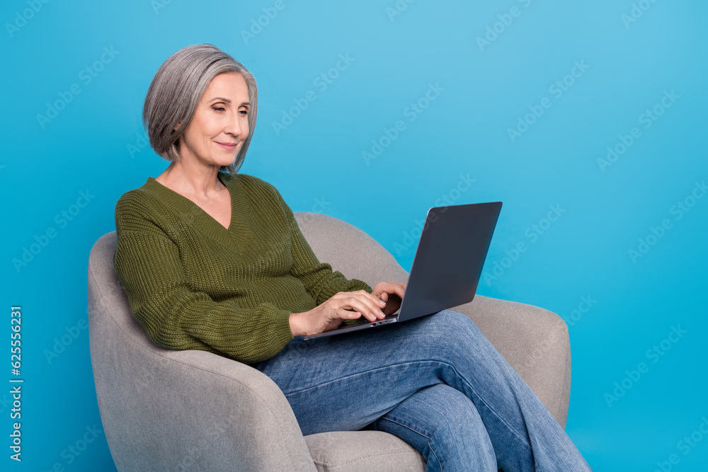 Naklejka premium Photo of satisfied senior businesswoman worker remote team leader project management sit chair typing laptop isolated on blue background