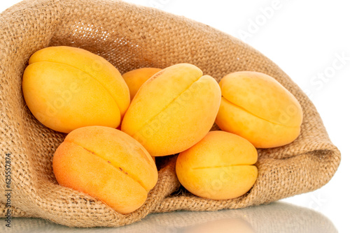 Several organic yellow apricots in a jute bag, macro, isolated on white background.