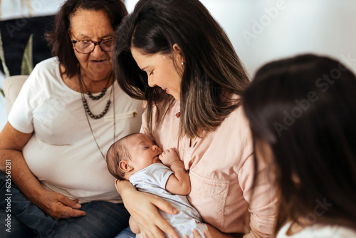 Multi-generation family sitting on sofa with newborn baby