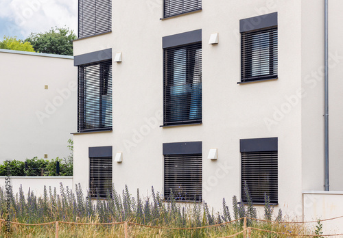 Shutter Windows of Modern White Elegant Minimalist Style House Apartment Building with Panoramic Windows and Landscaping. 