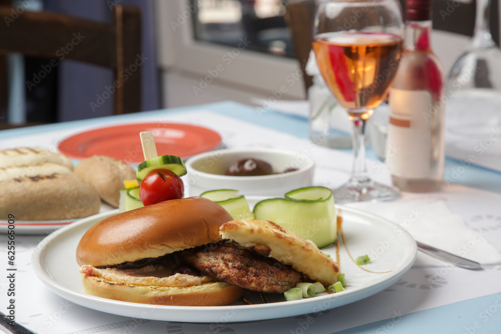 Fine casual dining: classic burger with cucumber slices served on the restaurant table Fine casual dining: classic burger with cucumber slices served on the restaurant table