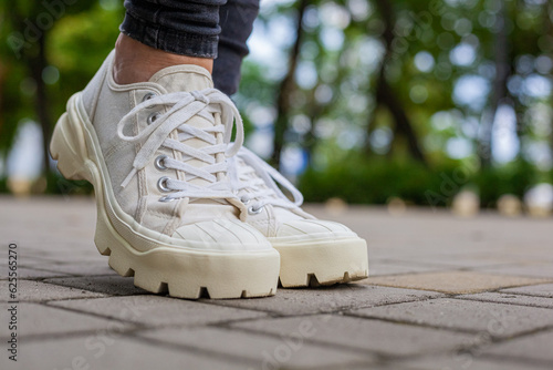 White sneakers with studded soles on female legs in black jeans