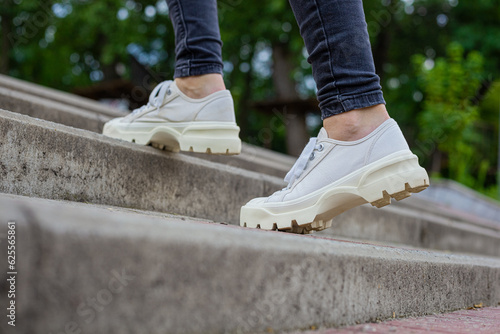 White sneakers with studded soles on female legs in black jeans