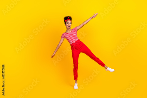 Full length photo of cute teen girl spread hands plane wings fooling wear trendy red striped garment isolated on yellow color background