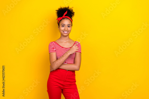 Photo of shiny adorable girl dressed red striped t-shirt pointing finger empty space isolated yellow color background