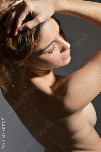 Belle femme au dos nu avec les mains dans les cheveux