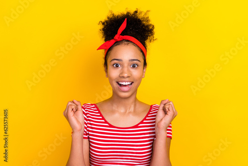 Photo of excited lucky lady wear striped red t-shirt rising fists screaming yes isolated yellow color background