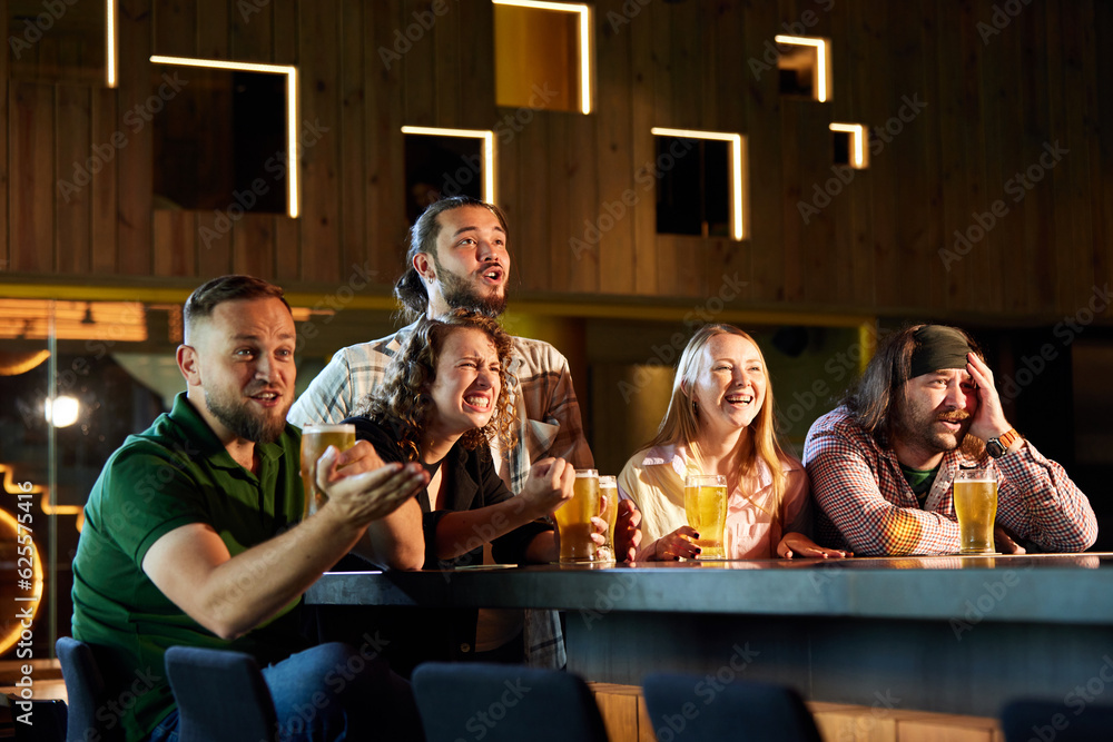 Group of friends meeting at pub, watching online football match translation, drinking beer, cheering up favourite team. Concept of sport competition, hobby, lifestyle, human emotions, fun