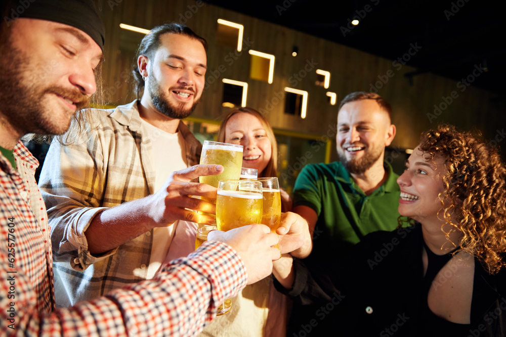 Young people, friends meeting together in pub, drinking beer, watching sport match, having fun, cheering up favourite team. Concept of sport competition, hobby, lifestyle, human emotions, fun