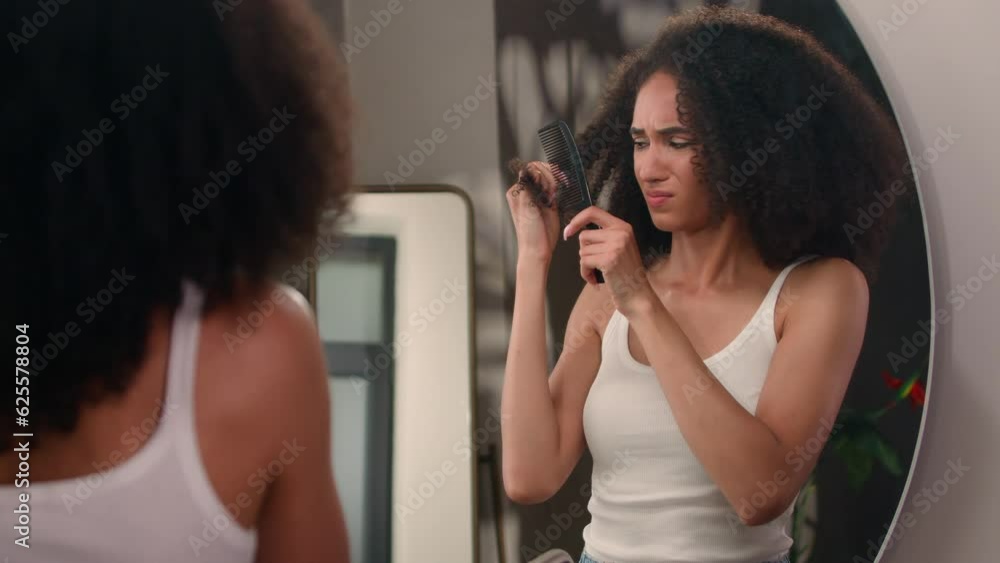 African American beautiful woman attractive girl sad haircare problem looking at mirror reflection upset female suffering dry hair trying to brush comb tangled damaged messy curls trouble hairstyle African American beautiful woman attractive girl sad haircare problem looking at mirror reflection upset female suffering dry hair trying to brush comb tangled damaged messy curls trouble hairstyle