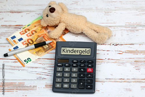 Kindergeld: Euro Banknoten mit Teddybär und das Wort Kindergeld auf dem Display eines Taschenrechners.