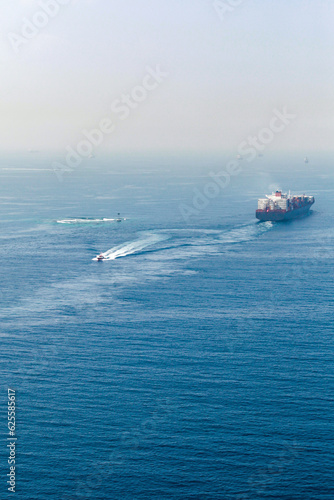 Container ship and a Pilot boat sail the Red Sea © evannovostro
