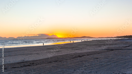 Beach Ocean Sea Water Coastline as Sun is going down distant people walking the beach silhouette landscape