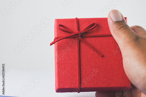 Male hand holding a red gift box on white background