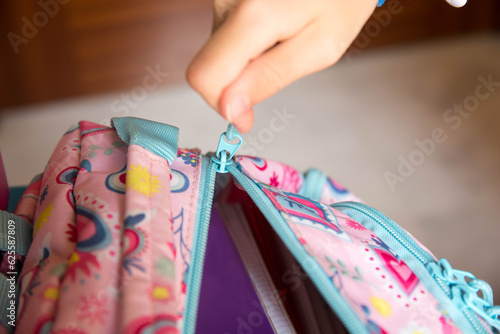 Mano de estudiante cerrando la mochila para la vuelta al colegio. Close up. 