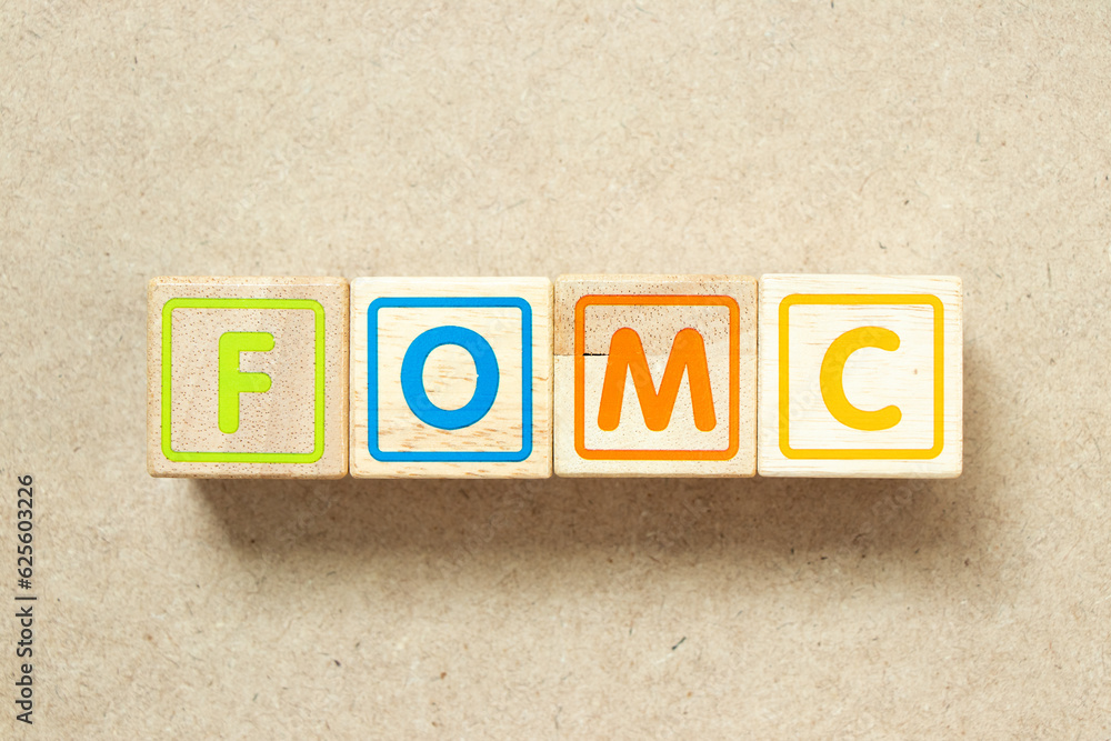 Wooden alphabet letter block in word FOMC (abbreviation of federal open market committee)  on wood background