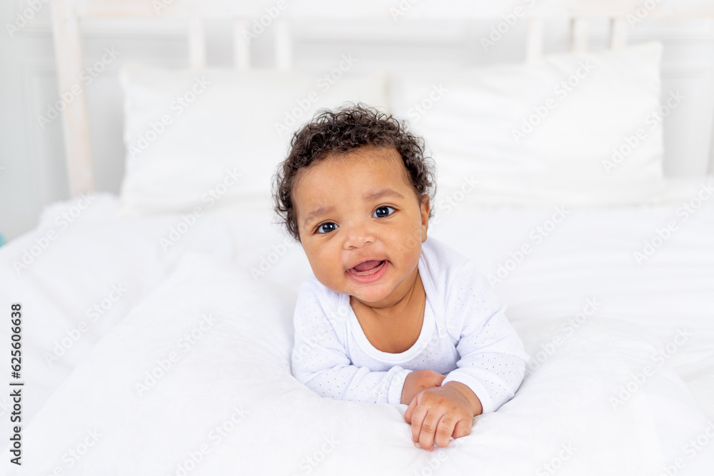 smiling African-American little baby on white bed in bedroom laughing smiling African-American little baby on white bed in bedroom laughing