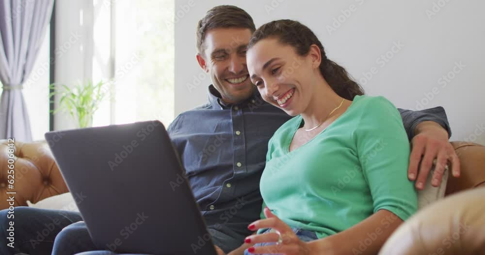 A young caucasian couple talking and paying their bills using a laptop A young caucasian couple talking and paying their bills using a laptop