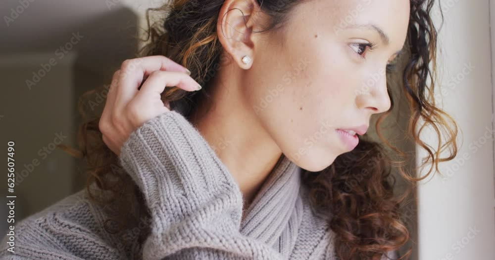 Portrait of thoughtful biracial woman standing at window and looking into distance Portrait of thoughtful biracial woman standing at window and looking into distance