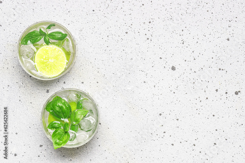 Fresh iced lemonade with lime and basil on light marble table top view, copy space for your design. Refreshing summer drink. © Iryna