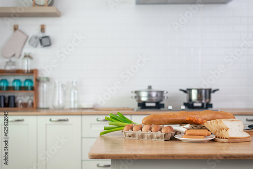 Baking materials are set out on a wooden table, ready for cooking. To copyspace text. Concept of cooking with a kitchen in the background. © chartphoto