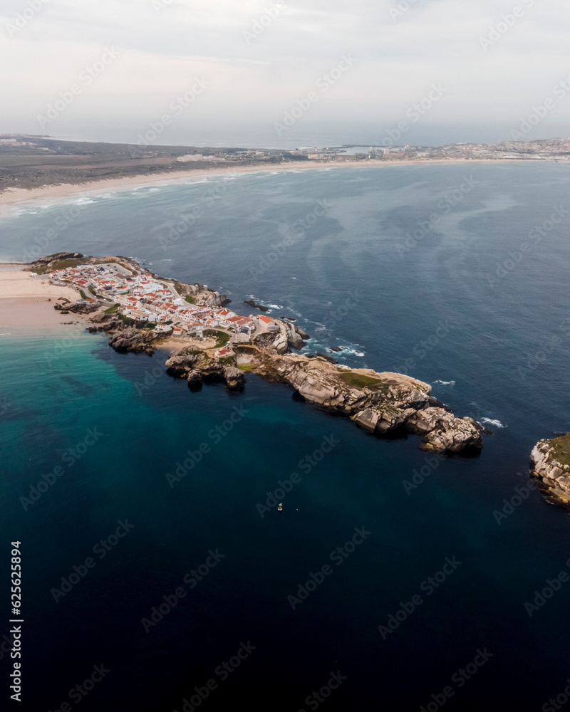 Aerial view of a small fishing boat moored off the Atlantic Ocean coastline in Balear, a small town on the island in Leiria district, Portugal. Aerial view of a small fishing boat moored off the Atlantic Ocean coastline in Balear, a small town on the island in Leiria district, Portugal.