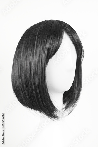 Natural looking black wig on white mannequin head. Medium length straight hair with bangs on the metal wig holder isolated on white background, side view