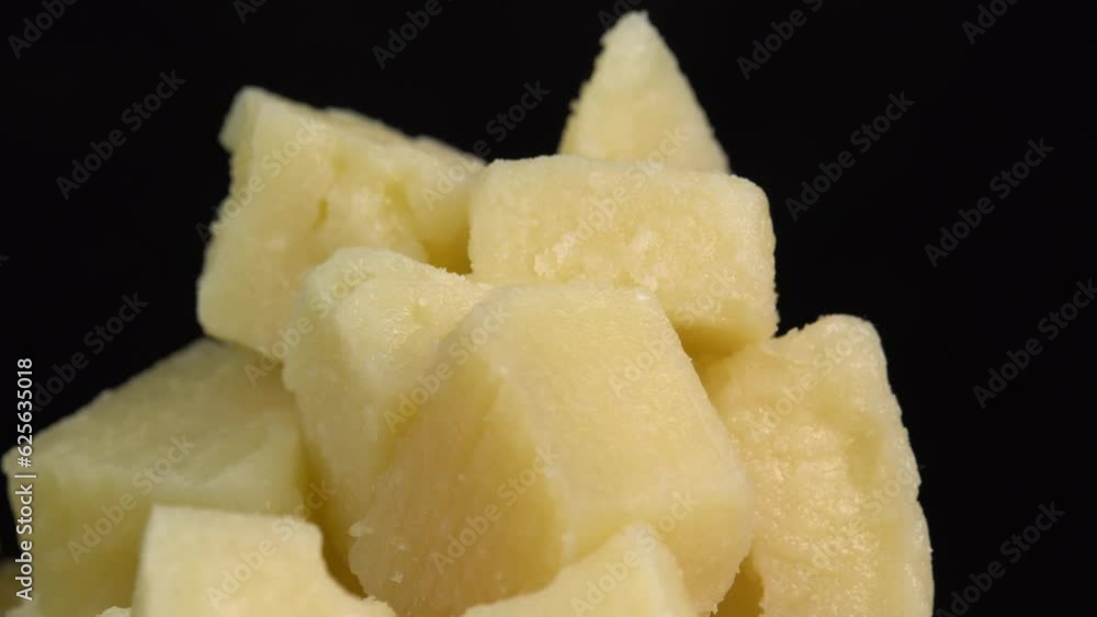 Pieces of parmesan cheese rotate on a black background. Firm aromatic aged cheese. Traditional Italian cheese grana parmigiano reggiano Pieces of parmesan cheese rotate on a black background. Firm aromatic aged cheese. Traditional Italian cheese grana parmigiano reggiano