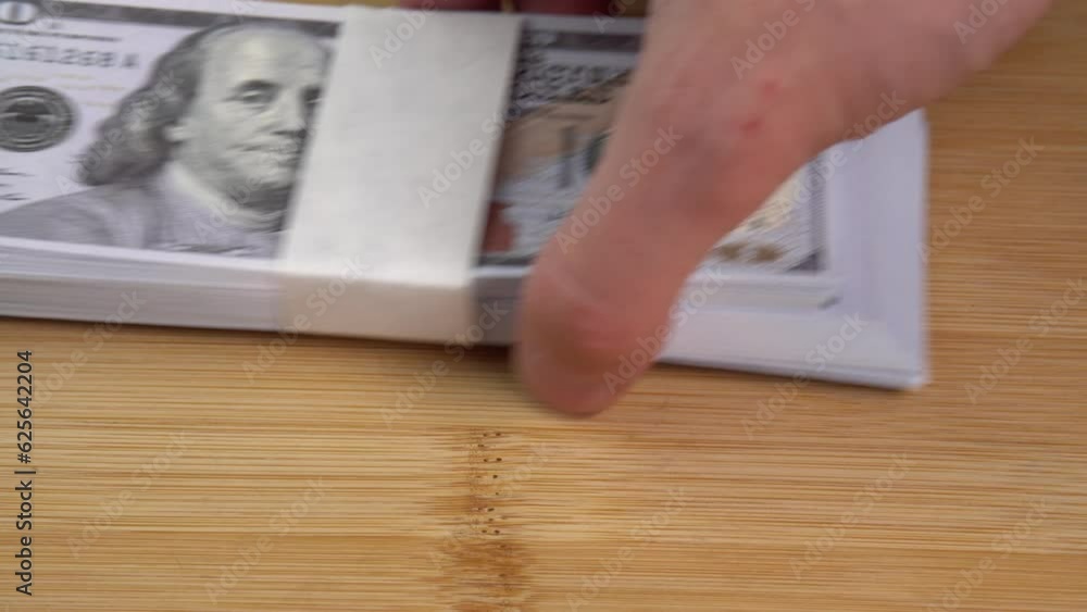 Stack of US dollars falls on the table. Counterfeiters check banknotes. Fight against economic crimes. Counting dollars. Demonstration wealth and luxury Stack of US dollars falls on the table. Counterfeiters check banknotes. Fight against economic crimes. Counting dollars. Demonstration wealth and luxury