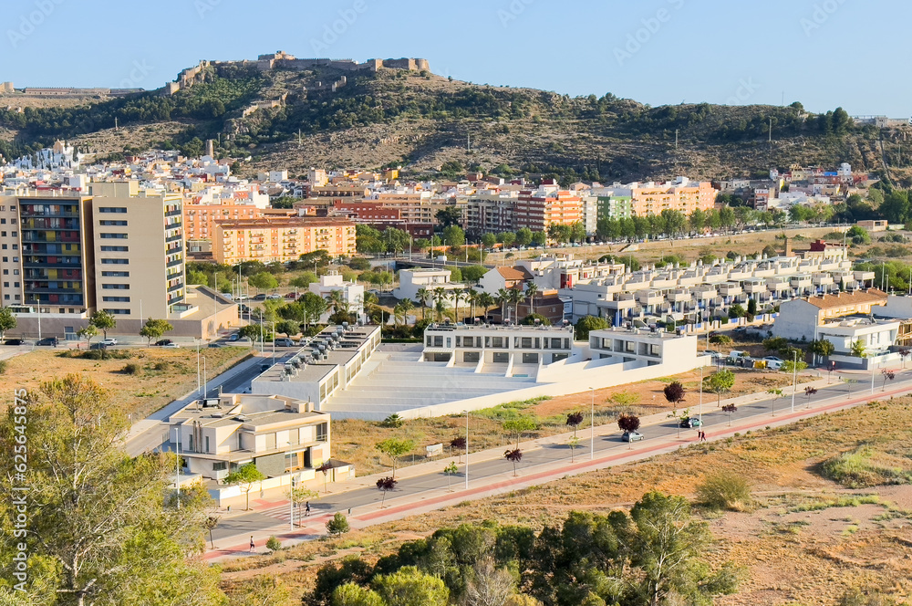 Buildings and houses in city, aerial view. Sagunto Castle on mountain. Ruins walls of Fortress Castle at town of Sagunto. Fortress Castillo in Mountains hills. Houses roofs in town at mountains. Buildings and houses in city, aerial view. Sagunto Castle on mountain. Ruins walls of Fortress Castle at town of Sagunto. Fortress Castillo in Mountains hills. Houses roofs in town at mountains.