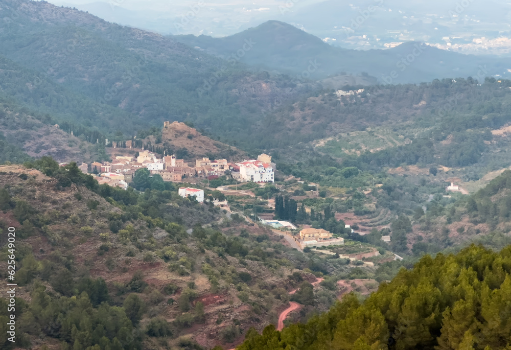 Obraz premium Town on Mountains landscape on sunset. Mountain view from Mola De Segart mountain in Sierra Calderona national park in Valencia, Spain.House in mountains. Landscape of a mountain valley.