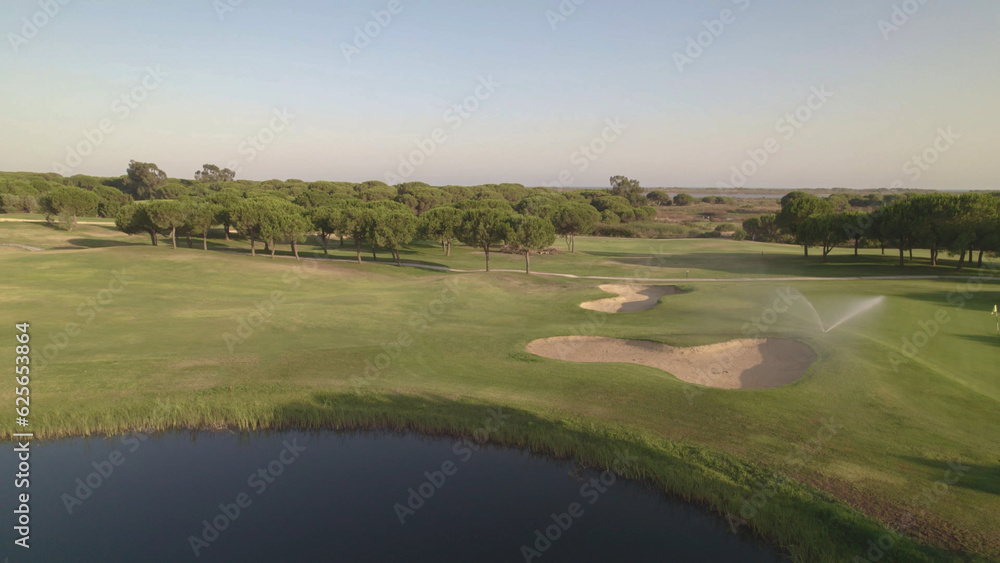 Golf course. Aerial view of greens, fairway, lake and sand bunkers on golf course at sunset. Spain. Golf course. Aerial view of greens, fairway, lake and sand bunkers on golf course at sunset. Spain.