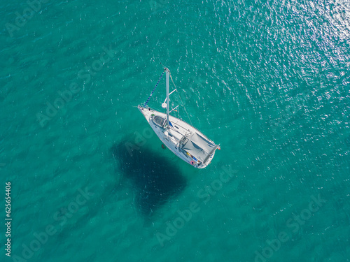 Sailboat anchored on sandbar with colorful turquoise water. Boat shadow on seabed. Aerial view from drone. Spain. © Siroco Drones