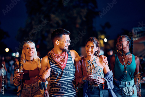Multiracial group of festival goers attending open air music concert at night.